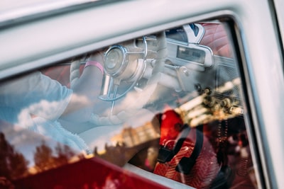 局部视图的一个司机在一个老式汽车通过后正确的窗口,重叠的玻璃上的反射。
